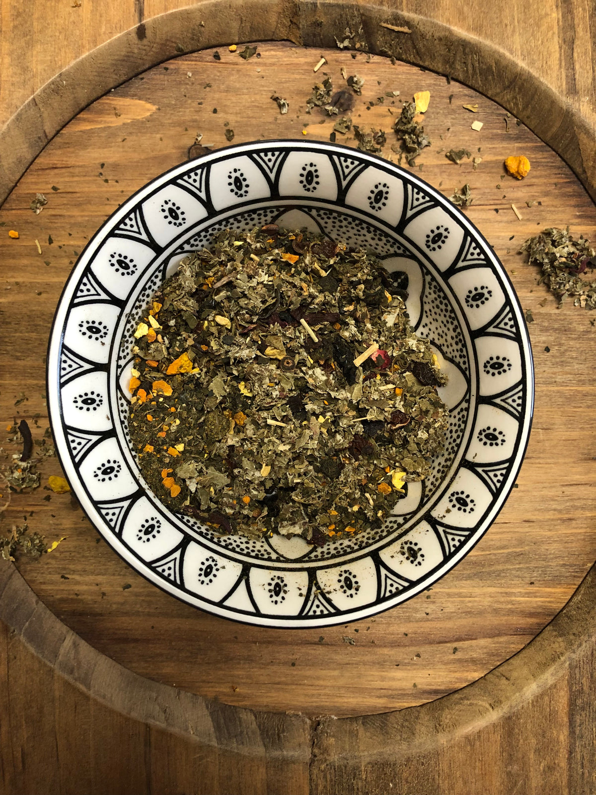 Vital Balance loose leaf herbal tea blend in a patterned ceramic bowl on a rustic wooden board.