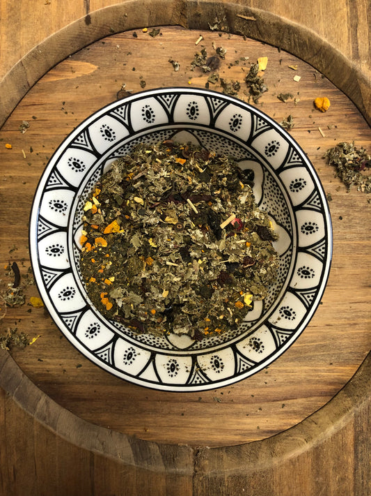 Vital Balance loose leaf herbal tea blend in a patterned ceramic bowl on a rustic wooden board.